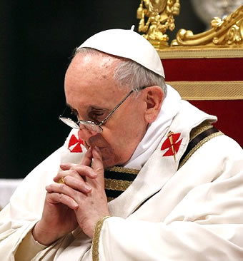 Pope Francis sits in chair while praying